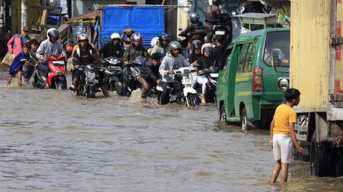 Pengguna jalan melintasi banjir yang merendam Jalan Raya Dayeuhkolot, di Kecamatan Dayeuhkolot, Kabupaten Bandung, Jawa Barat, Senin (3/11/2025).