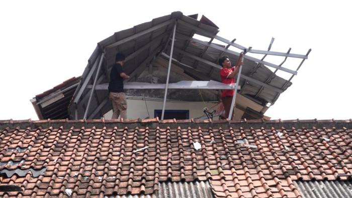 Dua orang warga membetulkan atap rumahnya yang rusak akibat disapu angin puting beliung, di RT 01, RW 07, Desa Pasanggrahan, Kecamatan Ujungberung, Kota Bandung, Jawa Barat, Rabu (5/11/2025).