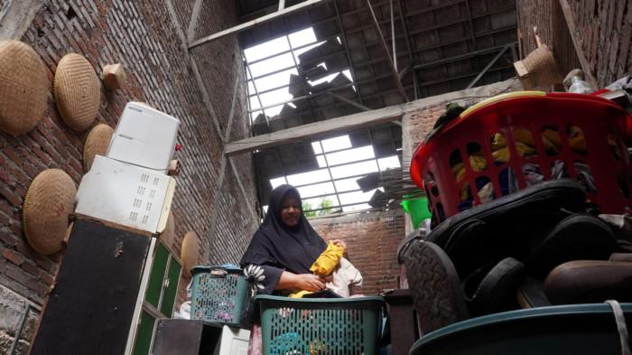 Seorang warga membereskan pakaian di dalam rumah dengan kondisi genting terbuka akibat disapu angin puting beliung, di RT 01, RW 07, Desa Pasanggrahan, Kecamatan Ujungberung, Kota Bandung, Jawa Barat, Rabu (5/11/2025).