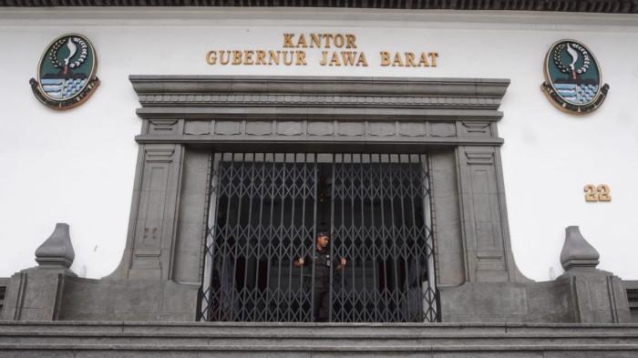 Petugas keamanan menutup pintu utama saat hari pertama penerapan work from home (WFH), di Gedung Sate, Kota Bandung, Jawa Barat, Kamis (6/11/2025).