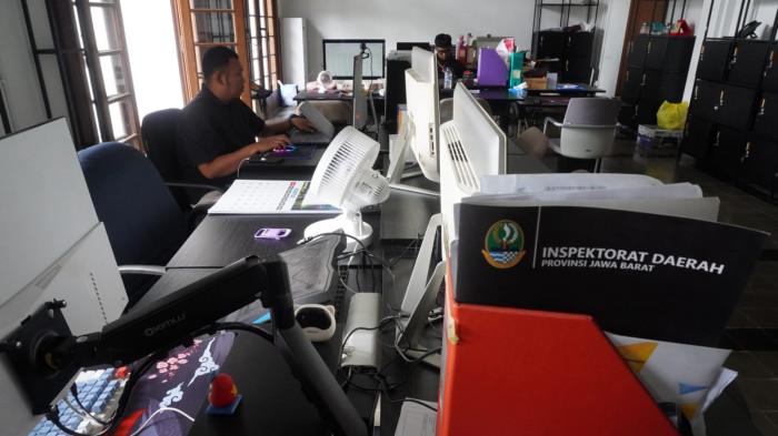 Dua orang aparatur sipil negara (ASN) menyelesaikan pekerjaan sementara sejumlah kursi lainnya tampak kosong dan lampu dipadamkan saat hari pertama penerapan work from home (WFH), di salah satu ruangan di Gedung Sate, Kota Bandung, Jawa Barat, Kamis (6/11/2025).