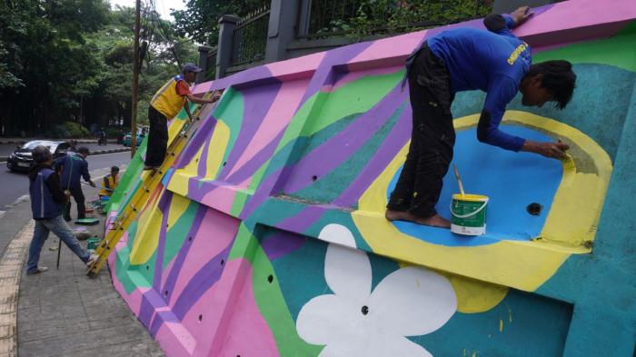Petugas mengecat saat finishing pembuatan mural pada dinding tembok di kawasan Babakan Siliwangi, Jalan Siliwangi, Kota Bandung, Jawa Barat, Jumat (7/11/2025).