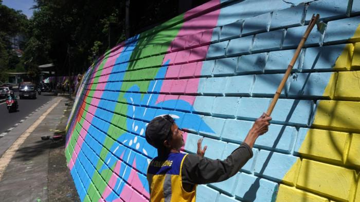Petugas mengecat saat finishing pembuatan mural pada dinding tembok di kawasan Babakan Siliwangi, Jalan Siliwangi, Kota Bandung, Jawa Barat, Jumat (7/11/2025).