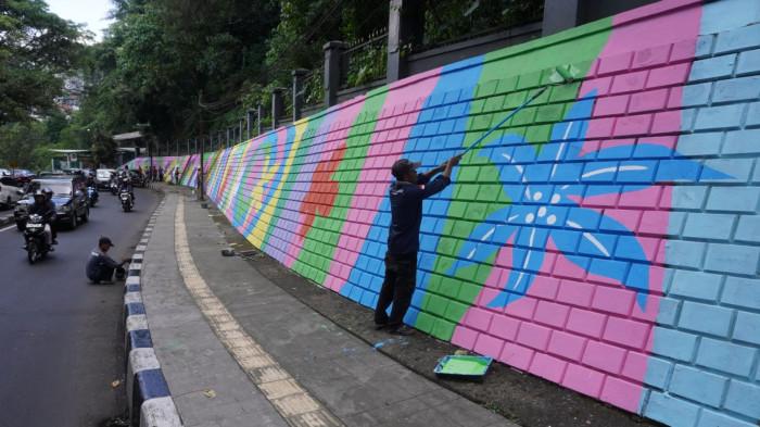 Petugas mengecat saat finishing pembuatan mural pada dinding tembok di kawasan Babakan Siliwangi, Jalan Siliwangi, Kota Bandung, Jawa Barat, Jumat (7/11/2025).