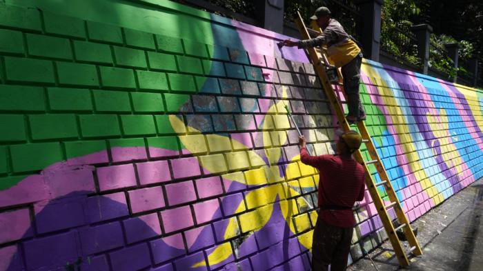 Petugas mengecat saat finishing pembuatan mural pada dinding tembok di kawasan Babakan Siliwangi, Jalan Siliwangi, Kota Bandung, Jawa Barat, Jumat (7/11/2025).