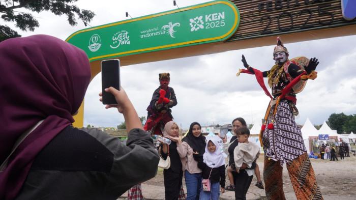 Pengunjung berfoto bersama dua tokoh wayang golek, Arjuna dan Cepot di gerbang masuk gelaran West Java Festival 2025, di Kiara Artha Park, Kota Bandung, Jawa Barat, Sabtu (8/11/2025).