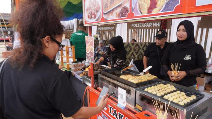 Pengunjung melakukan transaksi pembayaran non tunai dengan QRIS saat jajan kuliner pada gelaran West Java Festival 2025, di Kiara Artha Park, Kota Bandung, Jawa Barat, Sabtu (8/11/2025).