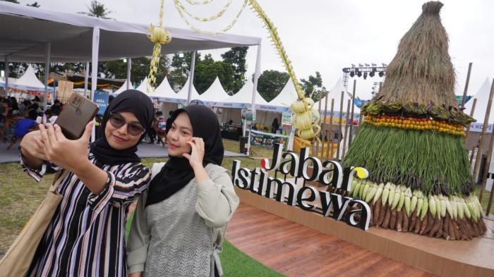 Pengunjung berswafoto di depan gunungan hasil bumi pada gelaran West Java Festival 2025, di Kiara Artha Park, Kota Bandung, Jawa Barat, Sabtu (8/11/2025).