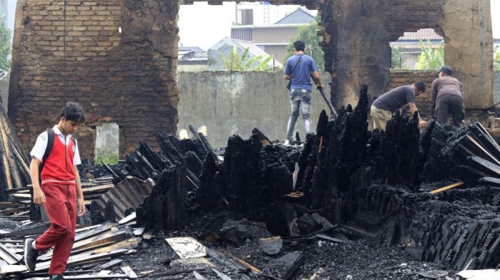 Pelajar melihat puing sisa kebakaran jongko kayu saat melintas di Jalan Terusan Pasirkoja, Kota Bandung, Jawa Barat, Rabu (12/11/2025).