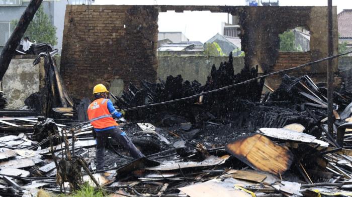 Petugas PLN memasang kabel listrik baru di antara puing sisa kebakaran jongko kayu di Jalan Terusan Pasirkoja, Kota Bandung, Jawa Barat, Rabu (12/11/2025).