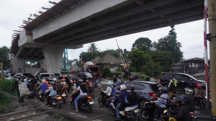 Kendaraan bermotor melintasi perlintasan sebidang kereta api di area proyek pembangunan Flyover Nurtanio, Jalan Abdurahman Saleh - Garuda, Kota Bandung, Jawa Barat, Jumat (14/11/2025).