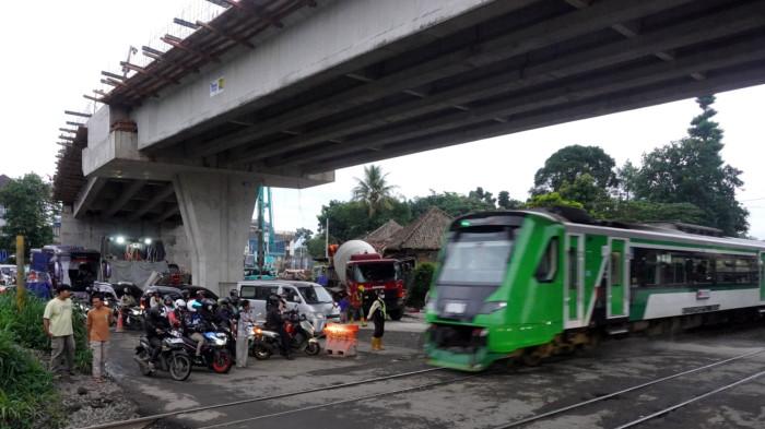 Laju kendaraan bermotor tertahan di perlintasan sebidang saat KA Feeder melintas di area proyek pembangunan Flyover Nurtanio, Jalan Abdurahman Saleh - Garuda, Kota Bandung, Jawa Barat, Jumat (14/11/2025).