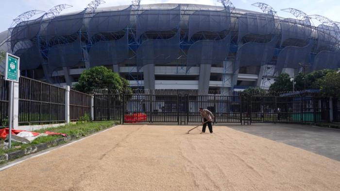 Petani menjemur gabah di depan gerbang Stadion Gelora Bandung Lautan Api (GBLA), Gedebage, Kota Bandung, Jawa Barat, Kamis (20/11/2025).