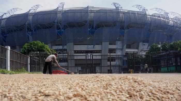 Petani menjemur gabah di depan gerbang Stadion Gelora Bandung Lautan Api (GBLA), Gedebage, Kota Bandung, Jawa Barat, Kamis (20/11/2025).