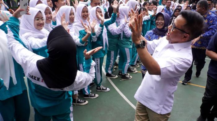 Menteri Koordinator Pemberdayaan Masyarakat (Menko PM), Muhaimin Iskandar, melambaikan tangan dan tersenyum saat diminta berswafoto oleh salah seorang pelajar saat kunjungan kerja dalam rangka Sosialisasi Program SMK Go Global, di SMKN 1 Bandung, Jalan Wastukencana, Kota Bandung, Jawa Barat, Senin (1/12/2025).