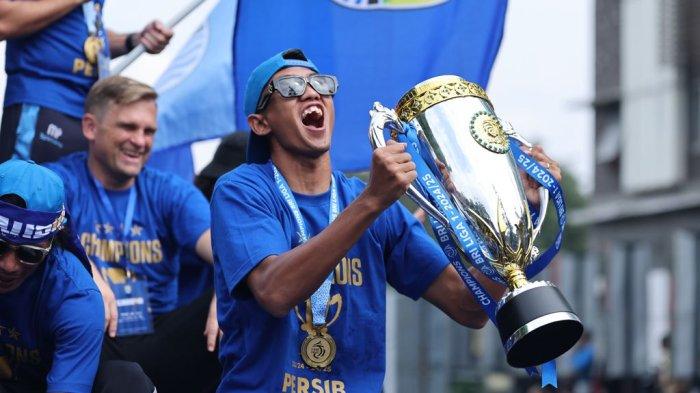 Bek PERSIB, Kakang Rudianto mengangkat trofi Liga 1 2024/25 pada konvoi juara di Kota Bandung, Minggu, 25 Mei 2025.