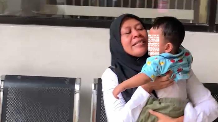 MENGGENDONG ANAK - Neni Nuraeni (37), ibu menyusui asal Karawang yang terjerat kasus fidusia di Karawang sedang menggendong anaknya.