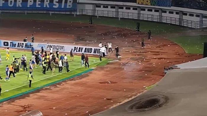 ADANG SUPORTER - Pemain, pelatih, hingga staf Persib Bandung mengadang oknum suporter dari tribun bagian selatan yang merangsek masuk ke lapangan setelah laga melawan Ratchaburi FC di Stadion Gelora Bandung Lautan Api (GBLA), Rabu (18/2/2026) malam dalam leg kedua babak 16 besar AFC Champions League Two (ACL 2) 2025/2026. Persib Bandung menang 1-0 tetapi kalah agregat 1-3.