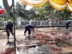 Panitia Masjid Istiqomah Membersihkan Paving Block dari Kotoran Sisa Kurban