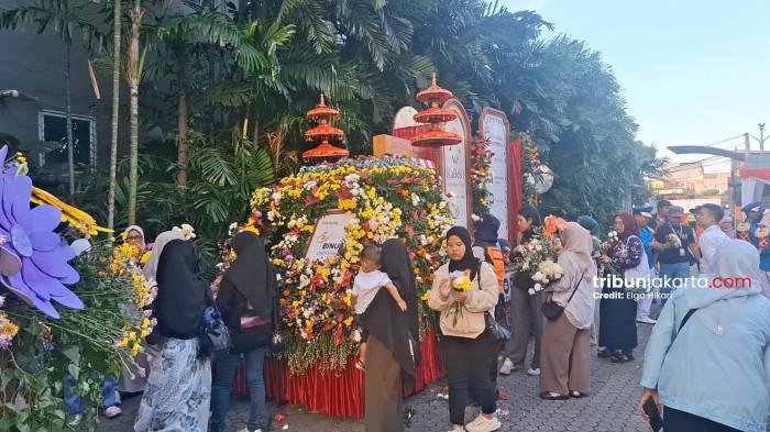 BEREBUT BUNGA - Masyarakat antusias mengambili bunga dan tanaman dari kendaraan hias seusai parade Jakarta International Flower Festival (JIFF) 2026, Minggu (14/6/2026).
