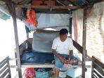 azis-50-sedang-duduk-di-bagian-belakang-perahu-sembari-memegang-ponsel-1.jpg