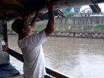 azis-menurunkan-spanduk-untuk-mencegah-air-hujan-masuk-di-sungai-ciliwung.jpg