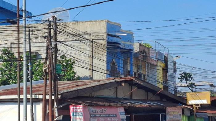 KABEL SEMRAWUT - Kabel jaringan internet di Jalan SK Rd Syahbudin, atau yang lebih dikenal masyarakat sebagai kawasan Simpang Puskes, Kota Jambi, menjuntai di sisi kiri dan kanan jalan, Kamis (28/5/2026).