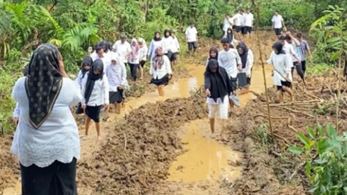 AKSI DAMAI - Puluhan guru dan staf SMAN 8 Bungo berjalan tanpa alas kaki melewati tanah berlumpur di Rantau Pandan, Rabu (29/4/2026). Aksi damai ini sebagai bentuk penolakan PETI di dekat lingkungan sekolah.