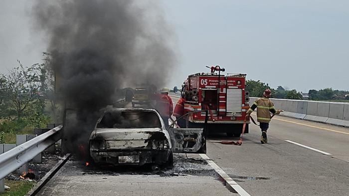 TERBAKAR - Petugas memadamkan mobil Toyota Corolla yang terbakar di jalan tol KM 397-700, Desa Sumbersari Kecamatan Ngampel Kabupaten Kendal. Tidak ada korban jiwa dalam kejadian tersebut.
 