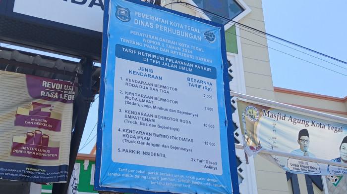 Papan informasi retribusi parkir berdasarkan Perda Nomor 1 Tahun 2024 tentang Pajak dan Retribusi Daerah yang terpampang di kawasan Alun-alun Kota Tegal, tepatnya di depan Masjid Agung Kota Tegal.