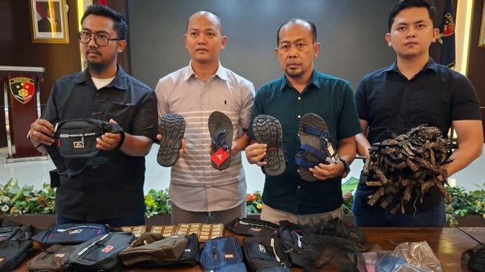 PRODUK PALSU - Perwakilan perusahaan PT Eigerindo Multi Produk Industri (MPI) dan Polisi menunjukkan sandal dan tas pinggang palsu mencatut nama produk ternama Eiger di Mako Ditreskrimsus Polda Jateng, Kota Semarang, Selasa (11/11/2025).