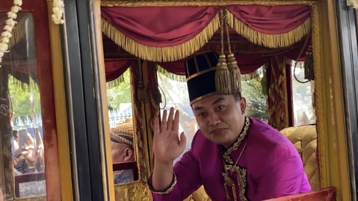 SAPA WARGA: PB XIV Purboyo senyum sumringah menyapa warga di atas kereta Grudha Kencana saat kirab jumenengan, Sabtu,(15/11/2025). PB XIV Purboyo mengenakan pakaian raja bewarna merah muda. (Tribun Jateng/Ardianti WS)