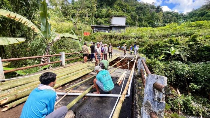GOTONG ROYONG - Warga Dusun Ngadisari, Desa Tlogodalem, Kecamatan Kertek, Kabupaten Wonosobo bergotong royong memperbaiki jembatan yang ambrol, Jumat (12/12/2025). Warga memperbaiki jembatan menggunakan bambu untuk akses sementara warga.
