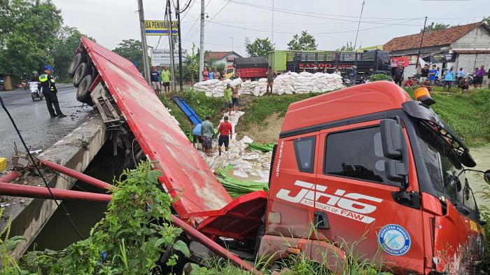 NYEMPLUNG KALI - Sebuah truk trailer bernomor polisi H 8237 OH terjun dari jembatan dan tercebur ke Sungai Kaliombo, Desa Ketitangwetan, Kecamatan Batangan, Kabupaten Pati, yang berada di tepi Jalan Pantura, Sabtu dini hari (13/12/2025).