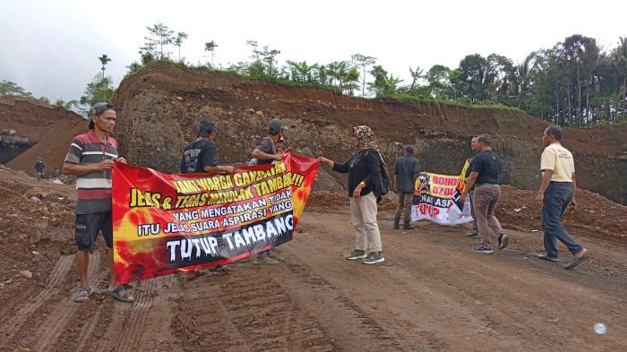 PENOLAKAN TAMBANG - Puluhan warga yang tergabung dalam Forum Aliansi Masyarakat Sumbang Peduli Lingkungan menggelar aksi bentang spanduk di Dusun Blembeng, Desa Gandatapa, Minggu (11/1/2026). Ahli tambang Unsoed, Ir Adi Candra ST MTmengatakan sepakat bahwa cara penambangannya membahayakan para pekerja tambangnya.