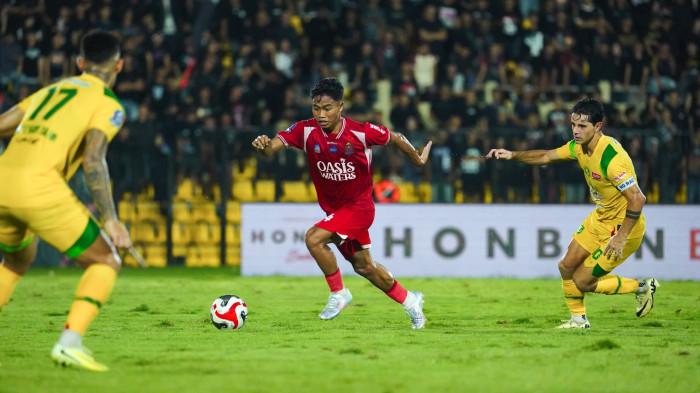 GIRING BOLA - Pemain Persijap Jepara, Rahmat Hidayat (baju merah) menggiring bola dari hadangan dua pemain Persebaya Surabaya, Sabtu (21/2/2026) di Stadion Gelora Bumi Kartini Jepara. Rahmat sempat mengalami insiden di atas lapangan dan harus menjalani perawatan medis. 