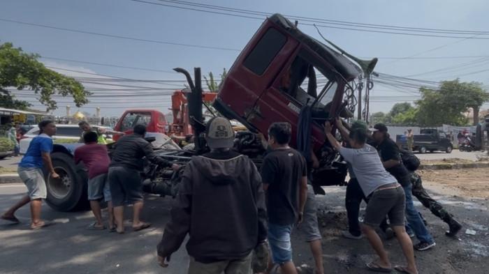 DORONG MUNDUR - Warga bersama-sama mendorong mundur kabin truk kontainer yang sebelumnya terguling untuk membuka kembali jalur menuju Mijen di Jalan Prof Dr Hamka, Ngaliyan, Kota Semarang, Jumat (10/4/2026). Kecelakaan beruntun yang terjadi di Silayur tersebut melibatkan truk kontainer, mobil Toyota Yaris, Mitsubishi Colt L300, sepeda motor, serta satu gerobak cilok.