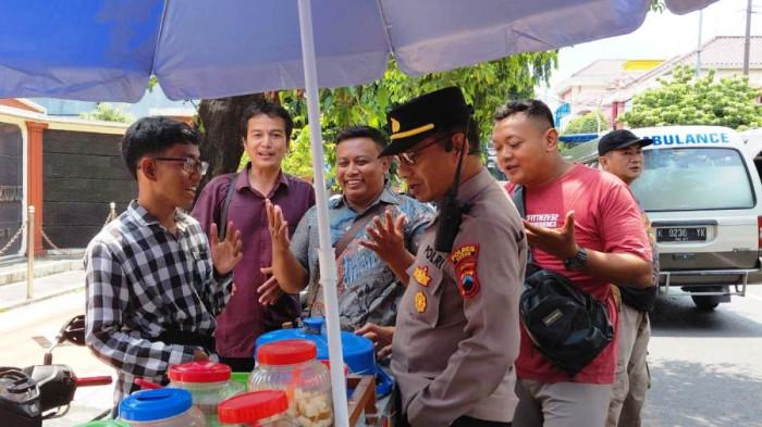 TEMUI PKL - Kapolsek Kudus Kota AKP Subkhan menemui Muhammad Anand Adiyanto saat berjualan di Jalan Sunan Muria Kudus, Selasa (14/4/2026). Anand adalah seorang korban pemerasan oknum ormas.