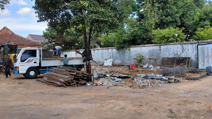 BONGKAR BANGUNAN - Sejumlah pekerja menggunakan alat berat dan armada monil truk membongkar dan mangangkut material bangunan di kawasan Penpada Kartini Jepara bagian belakang, Senin (18/5/2026). Kawasan tersebut akan dibangun Rumdin bupati dengan anggaran Rp 4 miliar tahun ini. 