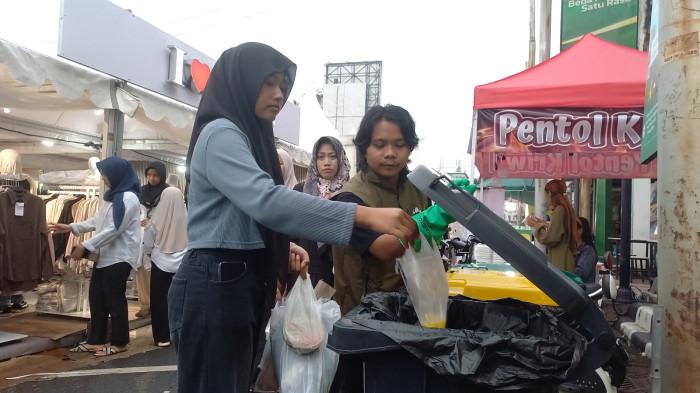 MEMBUANG SAMPAH - Salah seorang pengunjung Dandangan tengah membuabg sampah pada tempat sampah yang telah disediakan oleh Bakti Lingkungan Djarum Foundation, Senin (9/2/2026).