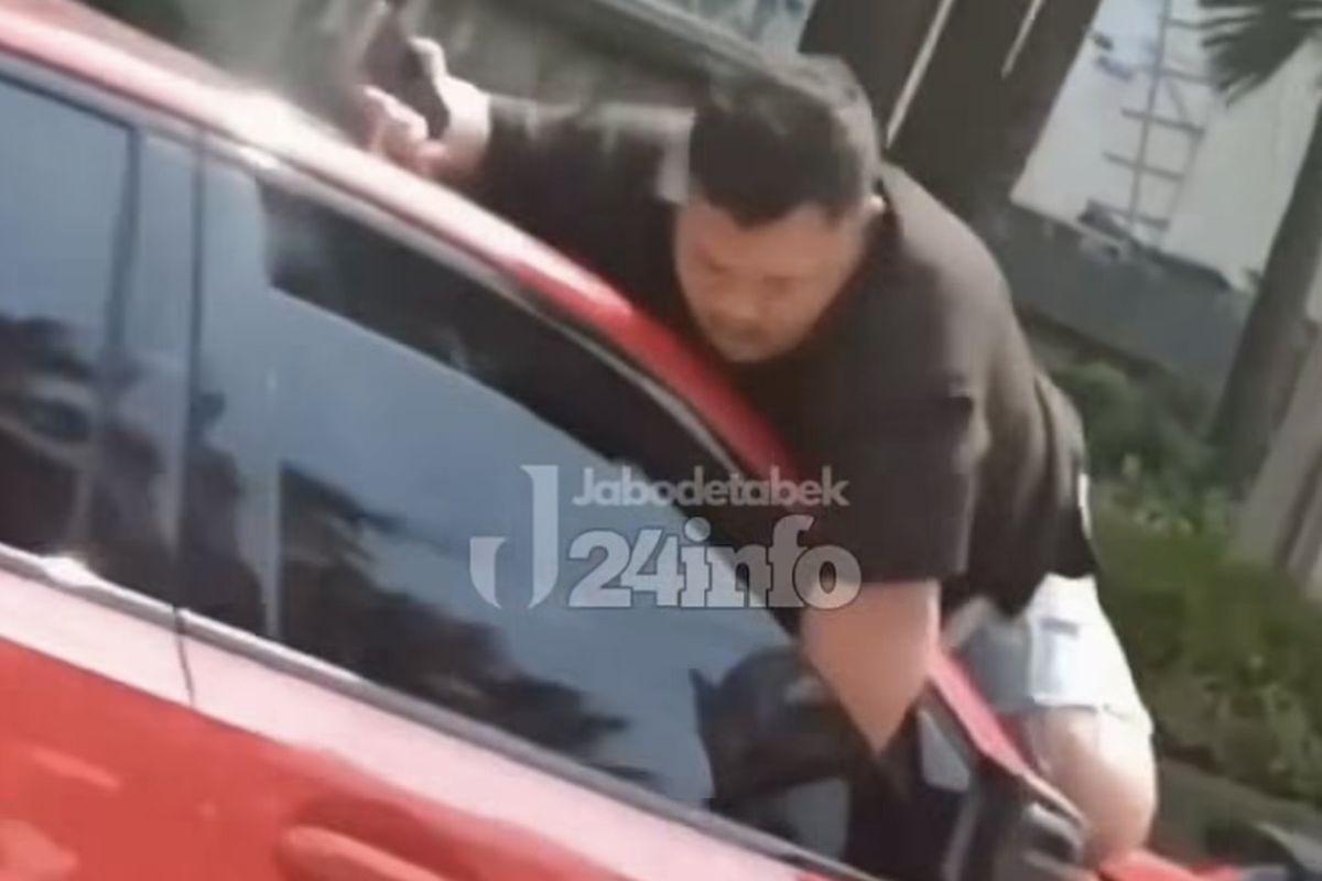 Seorang-pria-bergelantung-diatas-sebuah-mobil.jpg