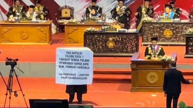 Wisudawan-membentangkan-spanduk-meminta-Kapolri-mengusut-tuntas-pelaku-pembunuh-ayahnya.jpg