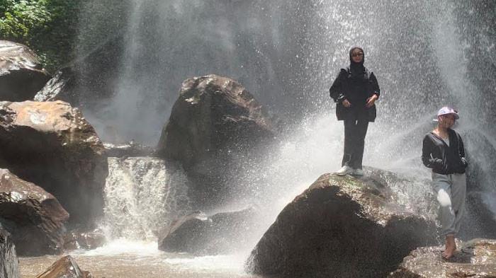 AIR TERJUN - Pengunjung berswafoto di bawah Air Terjun Pulo Agung di Desa Sukorejo, Kecamatan Sumberwringin, Bondowoso, kini viral digandrungi banyak orang, pada Rabu (4/2/2026).