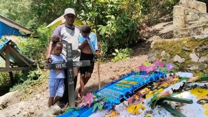 IBU HAMIL MENINGGAL - Abraham Kabey berfoto bersama kedua anak Irene Sokoy dan Niel Kabey di makam Irene Sokoy di Kampung Hobong, Distrik Sentani, Kabupaten Jayapura, Papua. Gubernur Papua, Mathius D Fakhiri, memastikan bakal mencopot dua Direktur RSUD buntut kasus Irene.