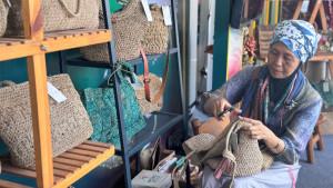 Faiqotul-Himmah-pendiri-UMKM-Daun-Agel-tengah-menata-produk-tas-di-Pameran-FESyar-2025.jpg