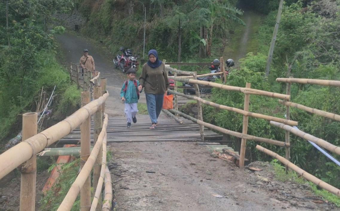 Sarmini-menggandeng-anaknya-melintasi-jembatan-darurat.jpg