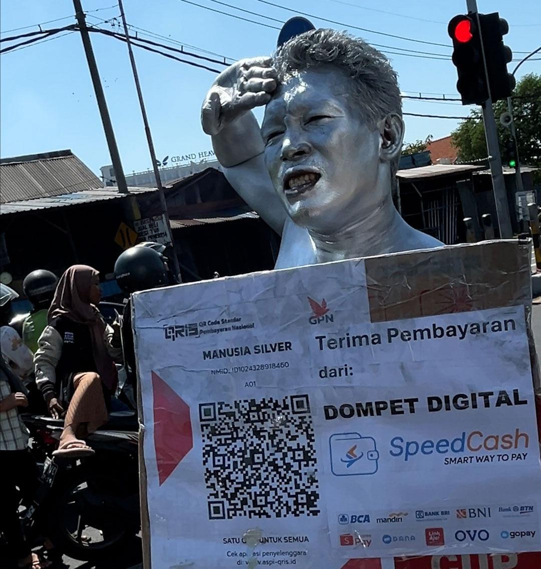 manusia-silver-tersebut-membawa-sebuah-kotak-yang-di-tempel-Qris-dompet-digital.jpg