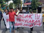 Para-wartawan-yang-tergabung-dalam-aliansi-jurnalis-Lamongan-berjalan-mundur-saat-demo.jpg