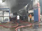 saat-petugas-pmk-berjibaku-padamkan-api-di-gudang-sandal-yang-terbakar-akibat-rambatan-api.jpg