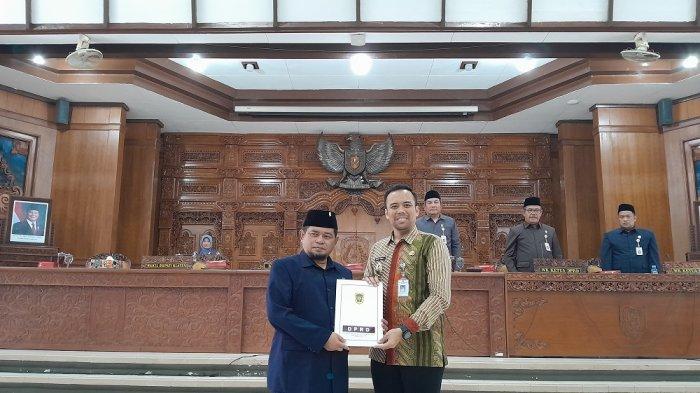 SERAHKAN DOKUMEN: Ketua DPRD Klaten, Edy Sasongko, menyerahkan dokumen tiga raperda yang disahkan menjadi perda kepada Wakil Bupati Klaten, Benny Indra Ardhianto, saat rapat paripurna Kamis (23/10/2025).